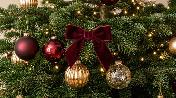 Bordeauxfarbene Samtschleife mit unterschiedlichen Glasornamenten und goldener Weihnachtsdeko