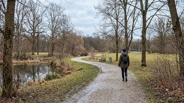 Erwachsene Person geht an einem hellen Wintertag in einem Park spazieren