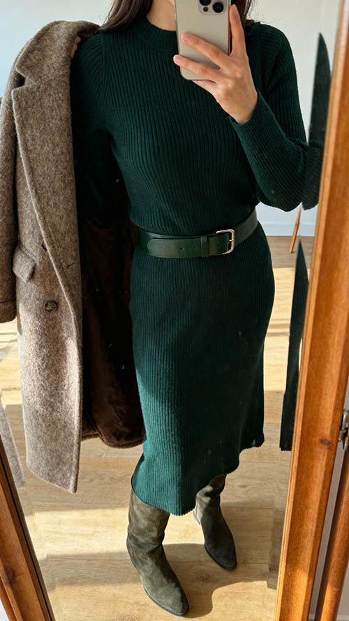 Frau trägt Strickkleid mit Gürtel und Stiefeln, iPhone-Selfie, elegantes Winter-Outfit