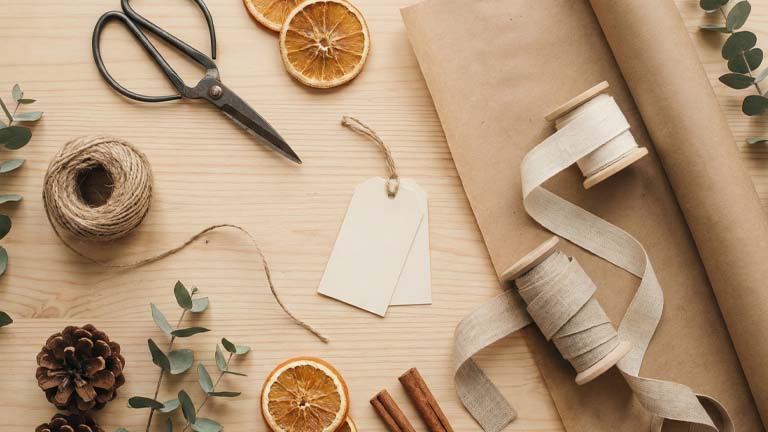 Auswahl an liebevoll und kreativ verpackten Geschenken mit Kraftpapier, Stoffbändern und Naturdeko auf einem hellen Tisch.