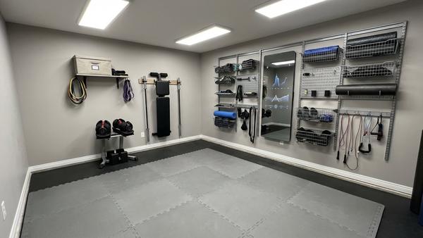 Ordentlich integrierte Homegym-Geräte mit Hantelständer, vertikal geparkter Bank und freier Trainingsfläche