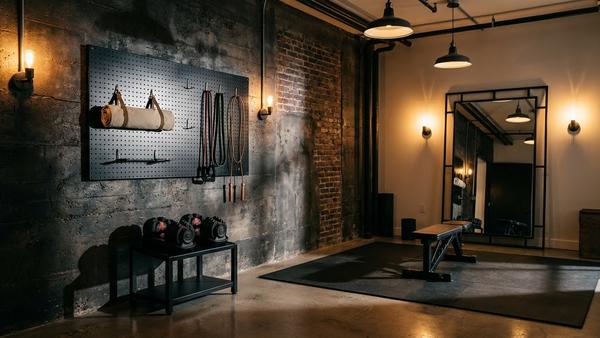 Industrial Homegym mit schwarzer Lochplatte, Kurzhanteln auf Metallständer und Spiegel mit dunklem Rahmen