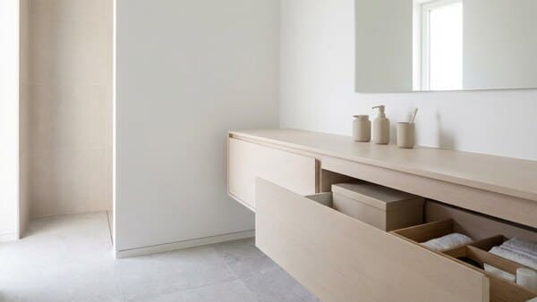 Minimalistisches Bad in Weiß, Grau und Beige mit glatten Flächen, geschlossenen Schränken und einheitlichen Spendern