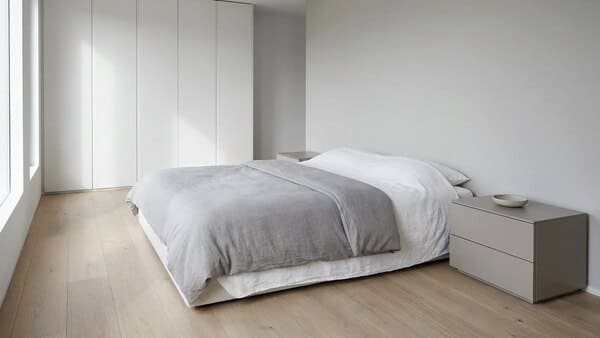 Minimalistisches Schlafzimmer mit wenigen Möbeln, klaren Linien und geschlossenen Stauraumlösungen.