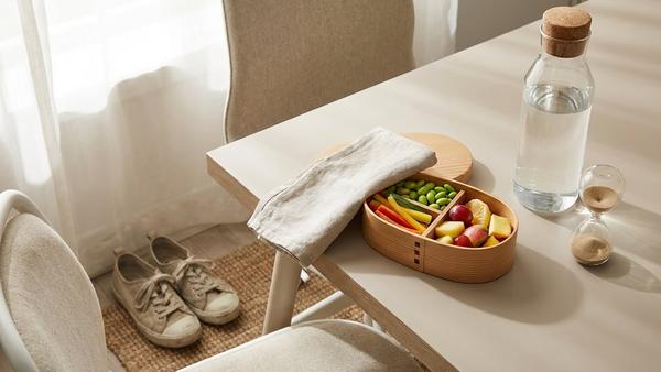 Schreibtisch mit Snackbox, Wasserflasche, Timer und Schuhen als Symbol für Pause und kurze Bewegung