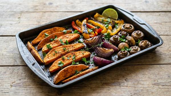 Geröstete Süßkartoffel-Wedges mit würzigem Cajun-Gemüse auf einer rustikalen Oberfläche.