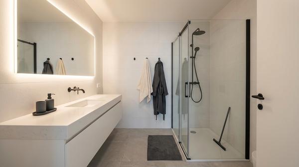 Weitwinkelaufnahme eines modernen Badezimmers in Weiß mit mattschwarzen Details und reduzierten Accessoires.