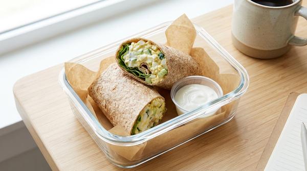 Aufgeschnittener Wrap mit leichtem Eier-Salat und Salat in einer Lunchbox.