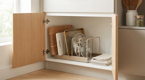 Küchenschrank mit vertikal aufgestellten Backblechen und Schneidebrettern in einem Trenngitter.