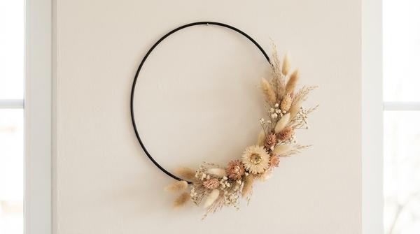 Du siehst einen Metallring mit einem Trockenblumen-Halbkranz in ruhigen Naturtönen.