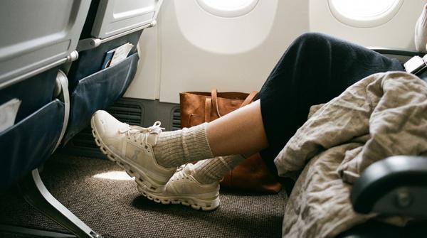 Eine Person streckt entspannt die Beine und Füße im Fußraum des Flugzeugs aus.
