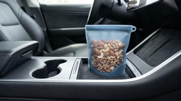 Ein kleiner, wiederverschließbarer Silikonbeutel mit Mandeln und Walnüssen steht ordentlich auf der Mittelkonsole im Auto.