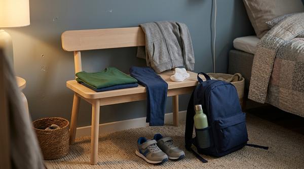 Vorbereitete Kinderkleidung, Schulrucksack und Trinkflasche für die Abendroutine vor dem nächsten Schultag