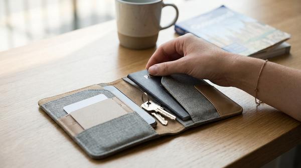 Reise-Organizer mit Reisepass, Smartphone, Karten und Schlüssel auf einem Tisch