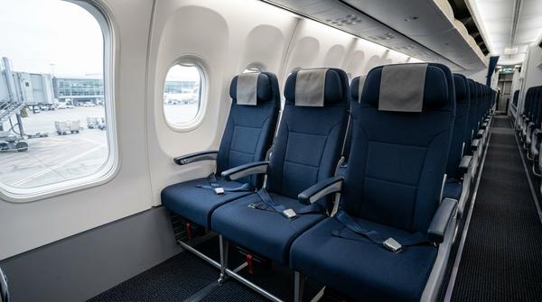 Leere Economy-Sitzreihe im am Gate stehenden Flugzeug mit Fenster-, Mittel- und Gangplatz